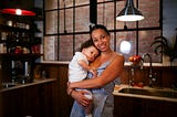 Young mother holding baby smiling in her kitchen