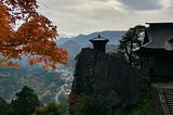 Iconic small temple on clifftop with moutains int he background