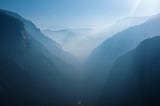 A mountainous valley cast in the bluish hue of the early dawn