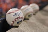 Three Major League Baseballs beside one-another, with the closest being in focus