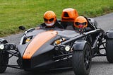 Sports car with riders wearing Halloween pumpkin helmets