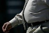 Cropped image of overweight man walking. Wearing a brown tie and kaki shirt and trousers.
