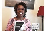 Nek’ka Migel, author holding the book God’s Prosperity, a Christian book about faith and money.