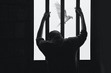 man holding prison bars while dove flies by