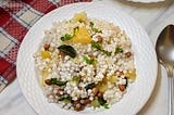 A plate of sabudana khichdi made of tapioca pearls, peanuts, potatoes and spices on a white background with red napkin.