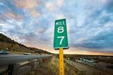 Mile marker on a road side with a bright blue sky above it.