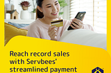 A smiling woman copies her credit card details into her phone while shopping online.