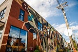 A colorful, abstract mural on the outside of a brick building.