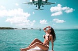 A woman looking at an airplane flying above her