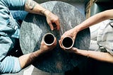 Photo taken from above of two people talking and drinking coffee