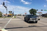 Photo of 4-lane street with restaurants and auto retailers.