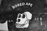 Image of a hoodie. On its back is the Bored Ape Yacht Club Logo.