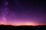 A shooting star against a purple sky and beyond, the universe