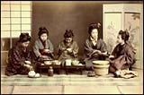 Five pre-modern Japanese women in kimono and old-fashion hairstyles eating lunch together.