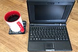 A black Eee pc next to a mug of coffee