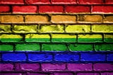image of a brick wall that seemingly has the colors of the LGBTQ+ rainbow flag painted on it
