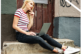 young woman sitting on steps with laptop