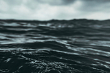 A closeup of the water in a stormy sea, clouds threatening in the distance