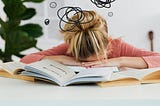 Student has her head down on her open text book