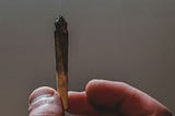 A hand holding a lit joint.