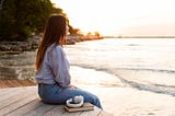 A woman looking at the sea at sunset.