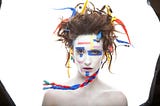 woman in white makeup with wires hanging off her hair and electrical tape on her face — ai vs human intelligent