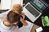 Woman sitting in front of Macbook with head in her hands