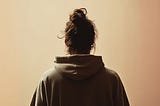Picture of a man with a messy bun from behind wearing a hoodie.