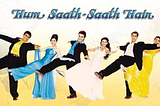 A poster shows 6 actors — 3 men and 3 women — and the words Hum Saath Saath Hai is visible on the top in blue. The 6 actors stand in a straight line with one leg in the air and both arms raised up on either side. The men are in black suits. The women are in traditional Indian attire and in gowns.