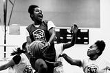 Girl basketball player going in for the dunk with an expression of joy and delight