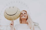 woman holding a smiley balloon