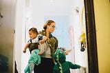 Mother with children standing by door at home.