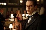 Man in 1920s tuxedo standing in dimly lit speakeasy nightclub