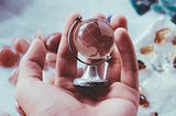 person holding globe paperweight in their hand