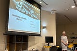 Jennifer standing in front of a screen following her presentation