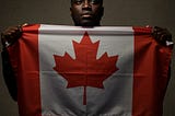 Black man with a concerned face holding Canadian flag