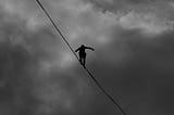 Black and white photo of tightrope walker in the sky