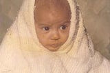Author as an infant wrapped in a blanket looking pensive