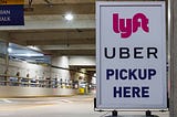Rideshare pick up area; sign reads: “Lyft. Uber. Pickup Here.”