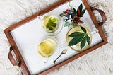 A tray shows tea with cannabis leaves in it.