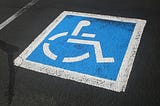 Photograph of the blue-and-white handicap symbol painted inside of a parking space.