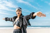 Woman with open arms on a beach looking into the camera