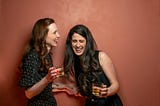 Two women holding a drink and laughing