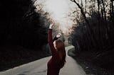 A woman in red dances on a dark rural road
