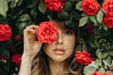 A young woman surrounded by some red roses