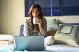 Person working in bed with a cup of coffee