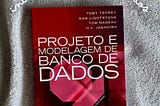 Imagem da capa do livro ‘Projeto e Modelagem de Banco de Dados’, segunda edição, publicado pela Elsevier. A capa tem um fundo vermelho escuro com elementos geométricos abstratos em tons de vermelho mais claro. Os nomes dos autores aparecem no topo da capa em letras brancas: Toby Teorey, Sam Lightstone, Tom Nadeau e H.V. Jagadish. O título do livro está em letras grandes e brancas no centro da capa. No canto inferior esquerdo está o logotipo da editora Elsevier.