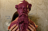 A bust of Charles Dickens is held aloft.