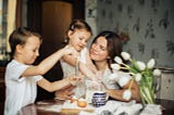 Mom with 2 kids cooking in the kitchen.