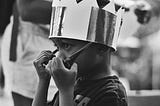 Boy wearing a toy crown, taking off his sunglasses